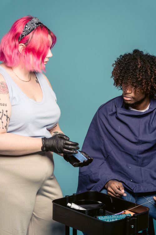 Cabeleireira com cabelo rosa mostrando opções de coloração para cliente em salão moderno