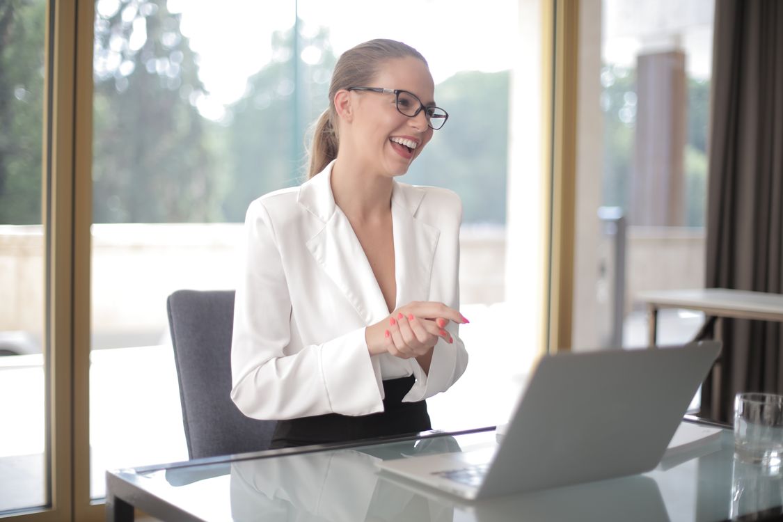 Mulher empreendedora sorrindo com notebook, representando maquiadora MEI organizando finanças e custos mensais